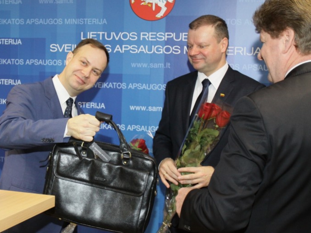 Sveikatos apsaugos ministrui Aurelijui Verygai (kairėje) portfelį įteikęs Sveikatos apsaugos ministerijos kancleris Gedeminas Aleksonis linkėjo kuo ilgiau jį išlaikyti. Nuotr. centre – premjeras Saulius Skvernelis.